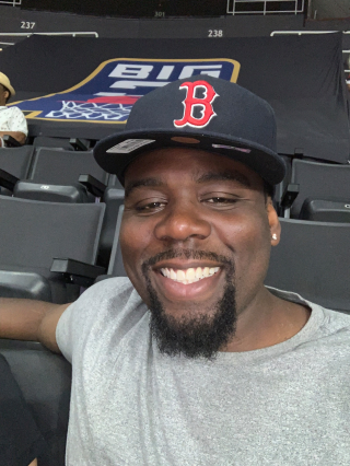 photo of James Campbell smiling, sitting in a stadium seat