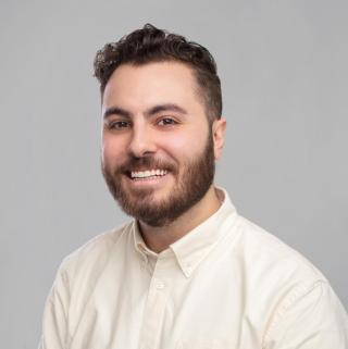 portrait of Jacob Cabral in a cream-colored dress shirt with a grey background.