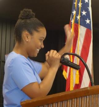 photo of student Anastacia Sampson waving at a podium