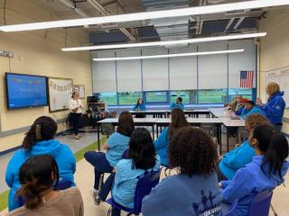 photo of group of students listening to a presentation from a business owner